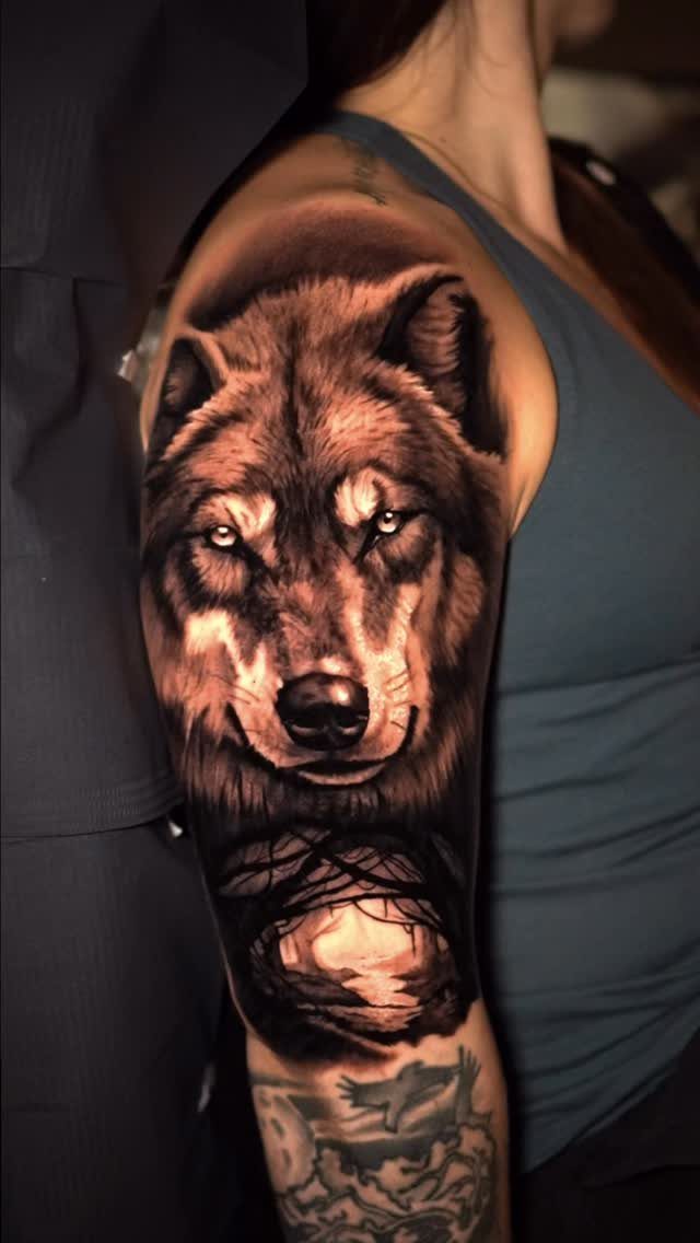 Wolf tattoo on an upper arm featuring a detailed realistic face and dark shading.