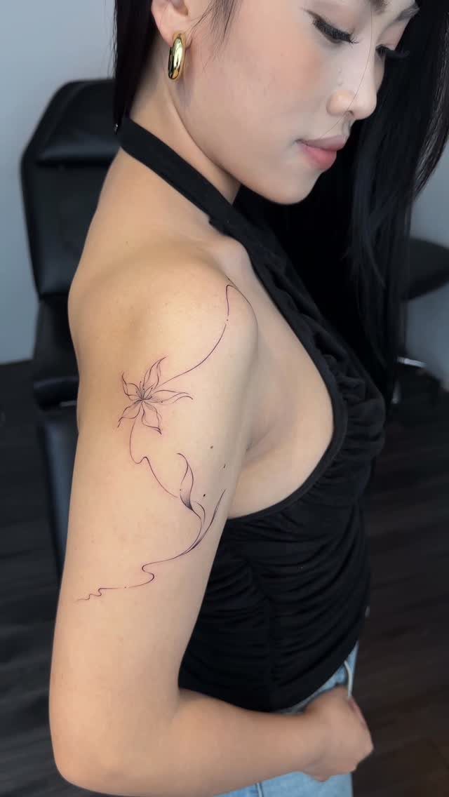 Woman with a dainty flower and vine tattoo on her upper arm