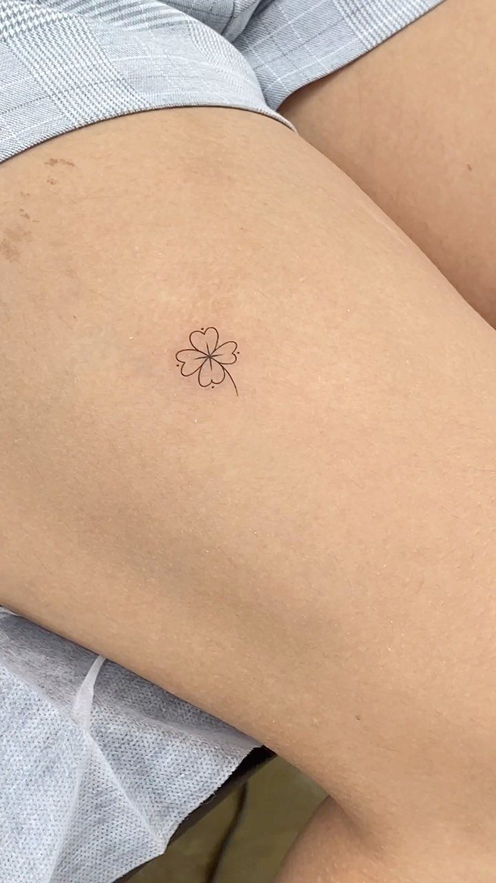 Small four-leaf clover fine line tattoo on a person's upper thigh.
