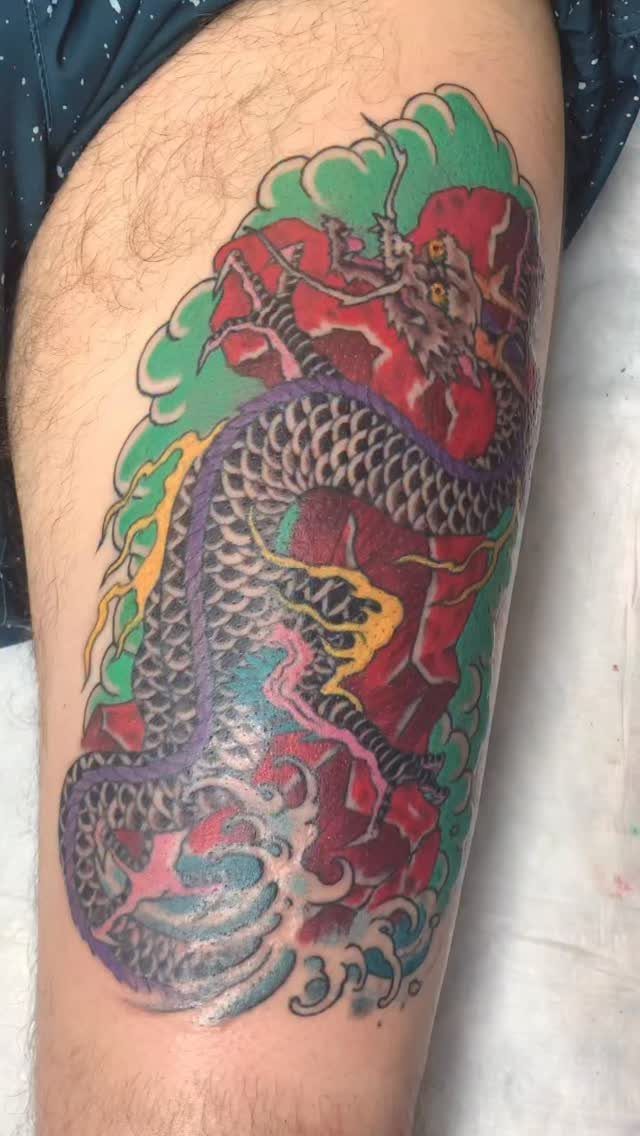 Dragon tattoo on an upper leg with red, green, and blue colors.