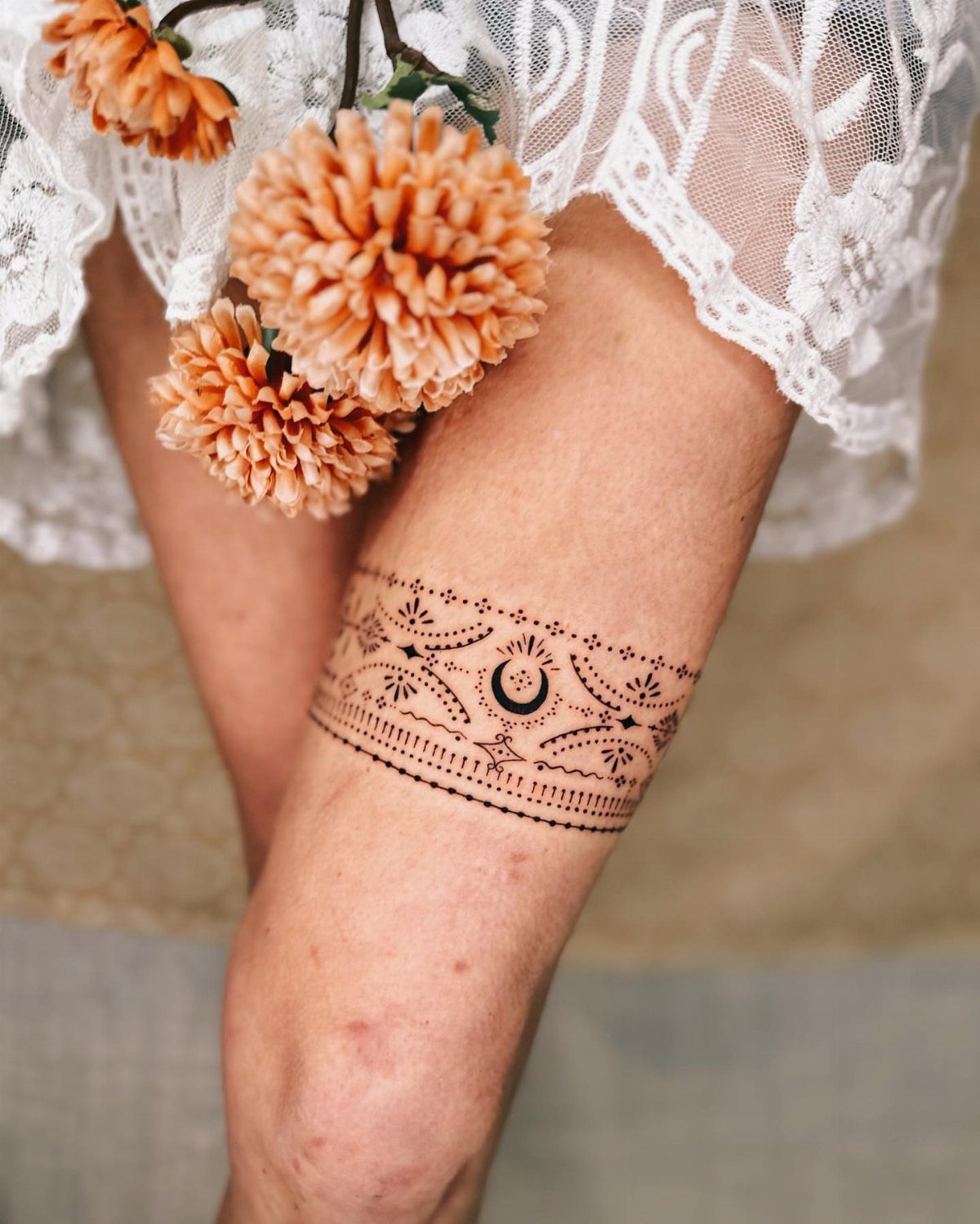 Upper leg with a black ink band tattoo featuring a crescent moon design.