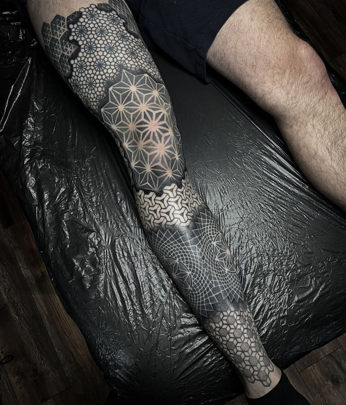 Geometric tattoo with intricate patterns covering a person's entire leg from thigh to ankle.