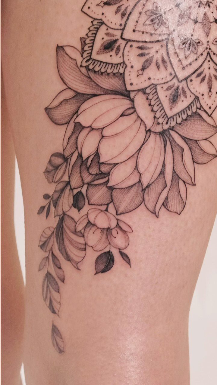 Lotus flower and mandala tattoo on a person's upper leg in black and grey.