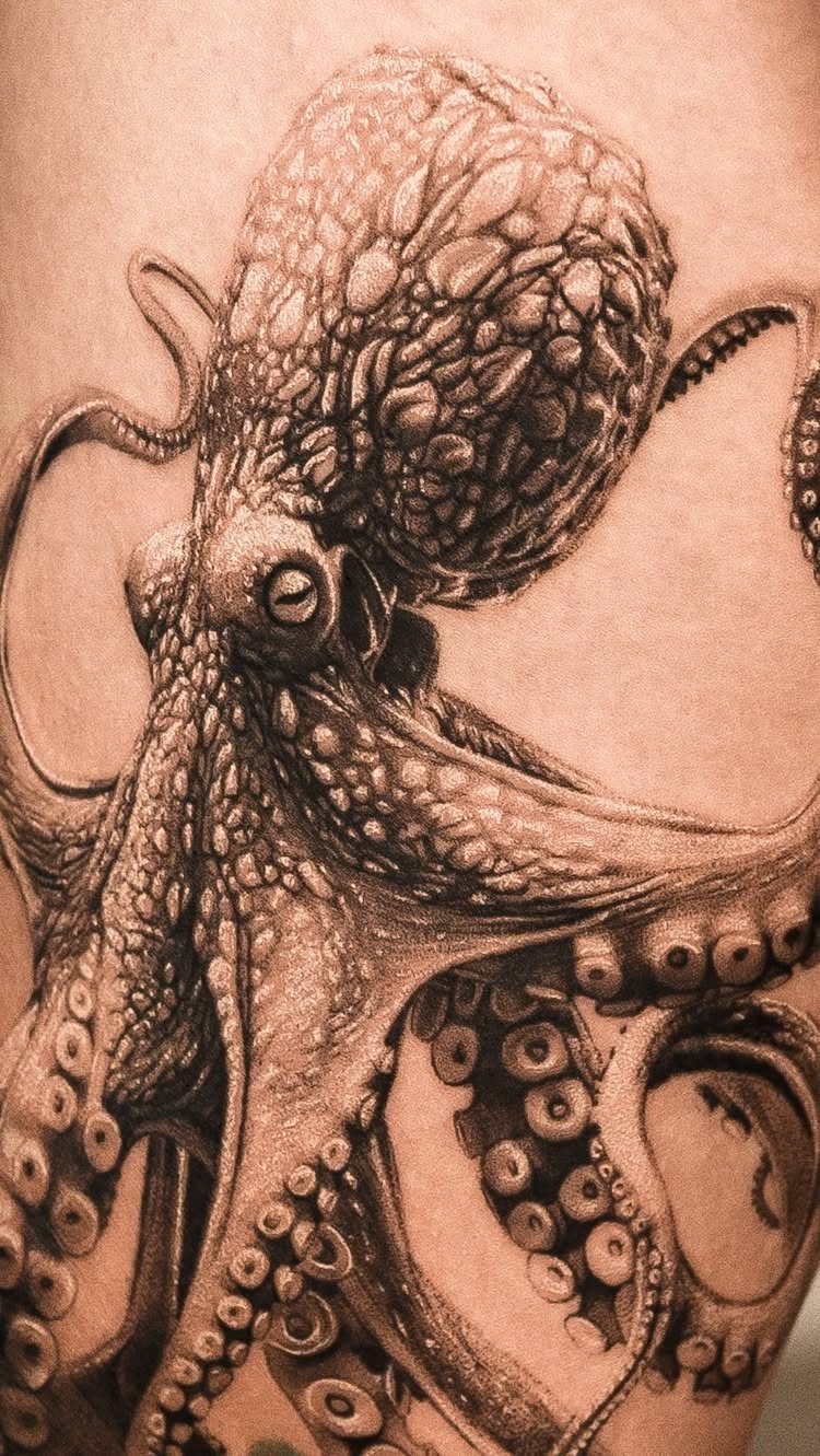 Detailed black and grey octopus tattoo on a person's upper leg skin.
