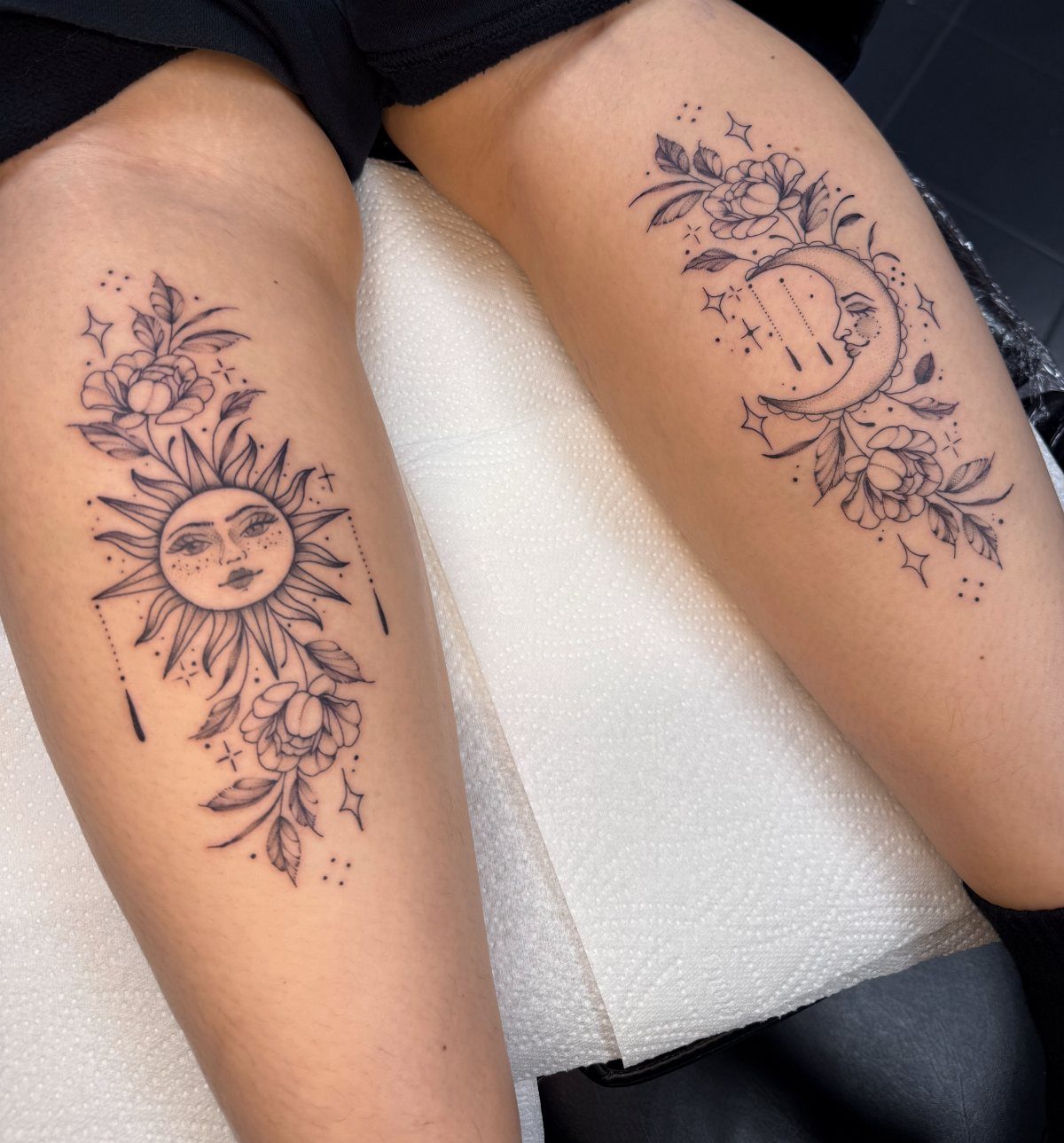 Sun and moon tattoos with floral accents on a person's upper thighs.