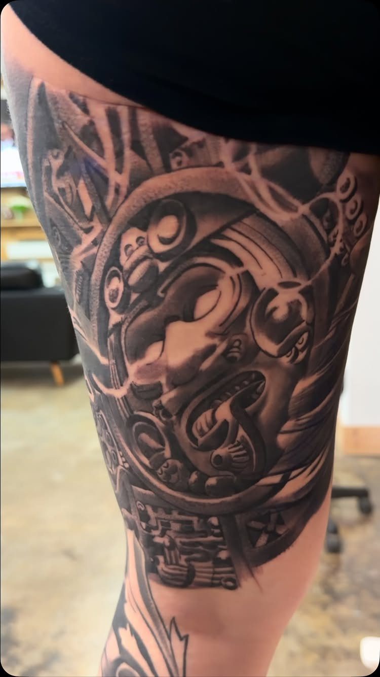 Detailed black and grey tribal tattoo on a person's upper leg thigh