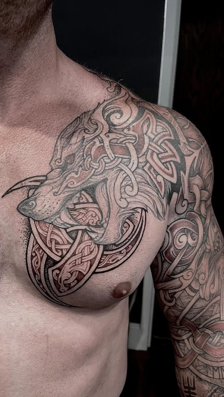 Wolf head tattoo with intricate Norse knotwork on a man's chest and shoulder