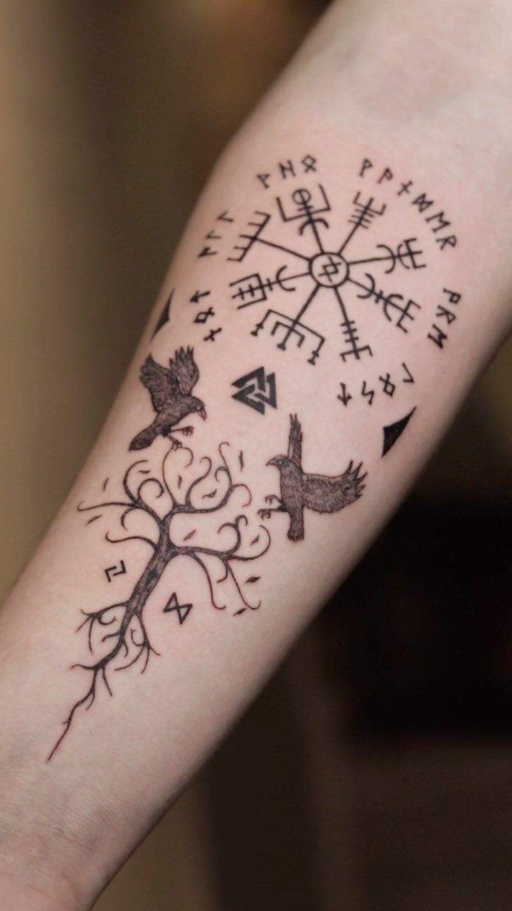 Viking tattoo on forearm featuring two ravens, a world tree, and a Norse compass.