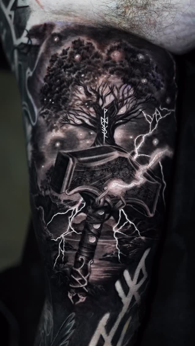 Thor's hammer tattoo with lightning bolts and a large tree on an arm.