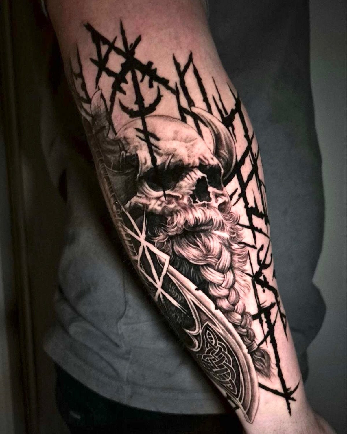 Viking skull tattoo with braided beard and shield on a man's forearm