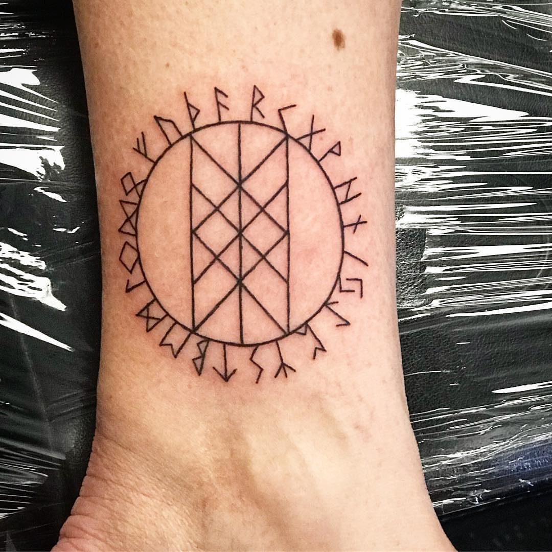 Wyrd web tattoo with surrounding runes on a person's ankle