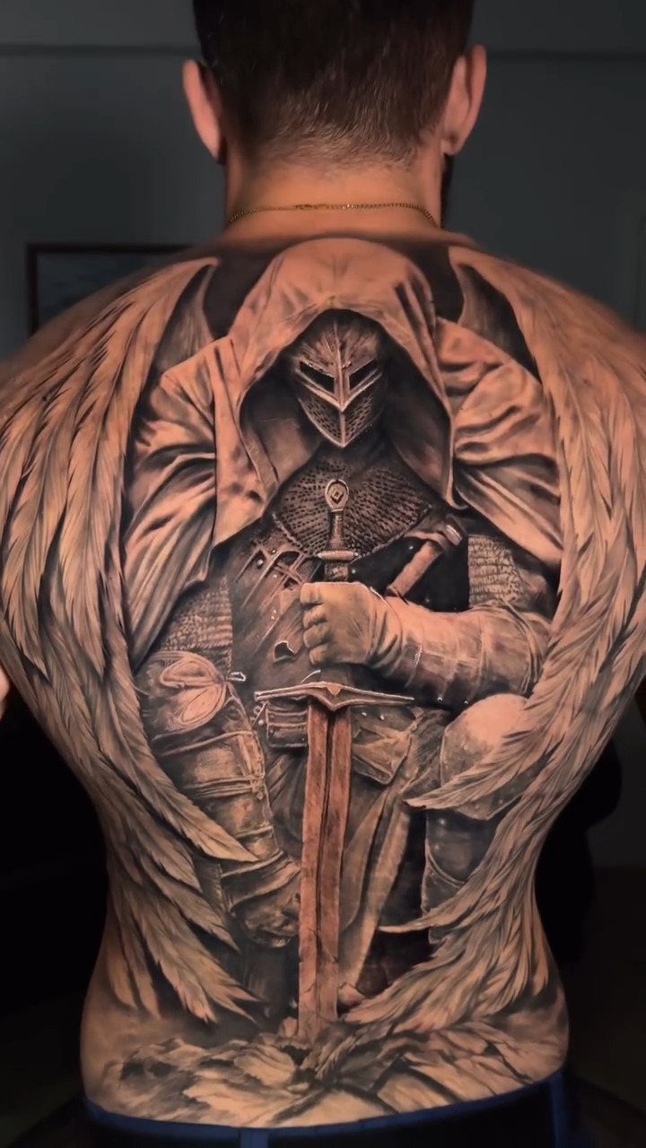Full back tattoo of a hooded knight with large black and grey wings.