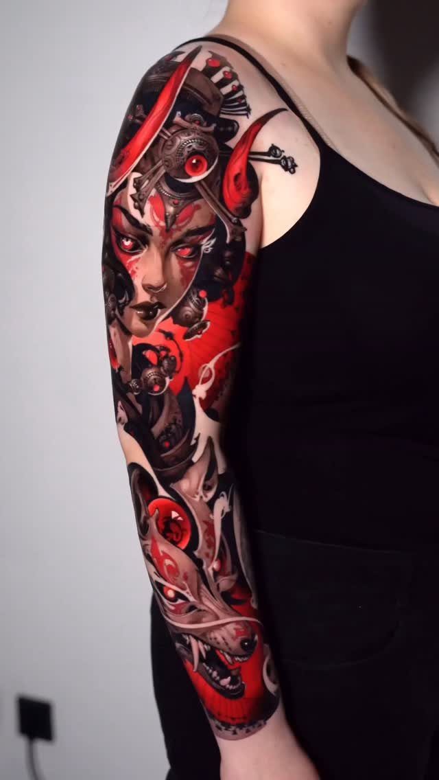 Woman's arm with a full sleeve tattoo in striking red and black ink.