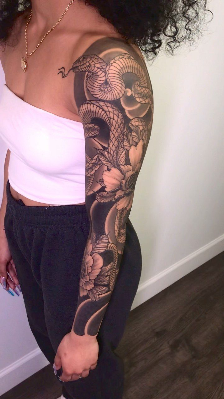 Woman with a full sleeve Japanese tattoo of a snake and flowers.
