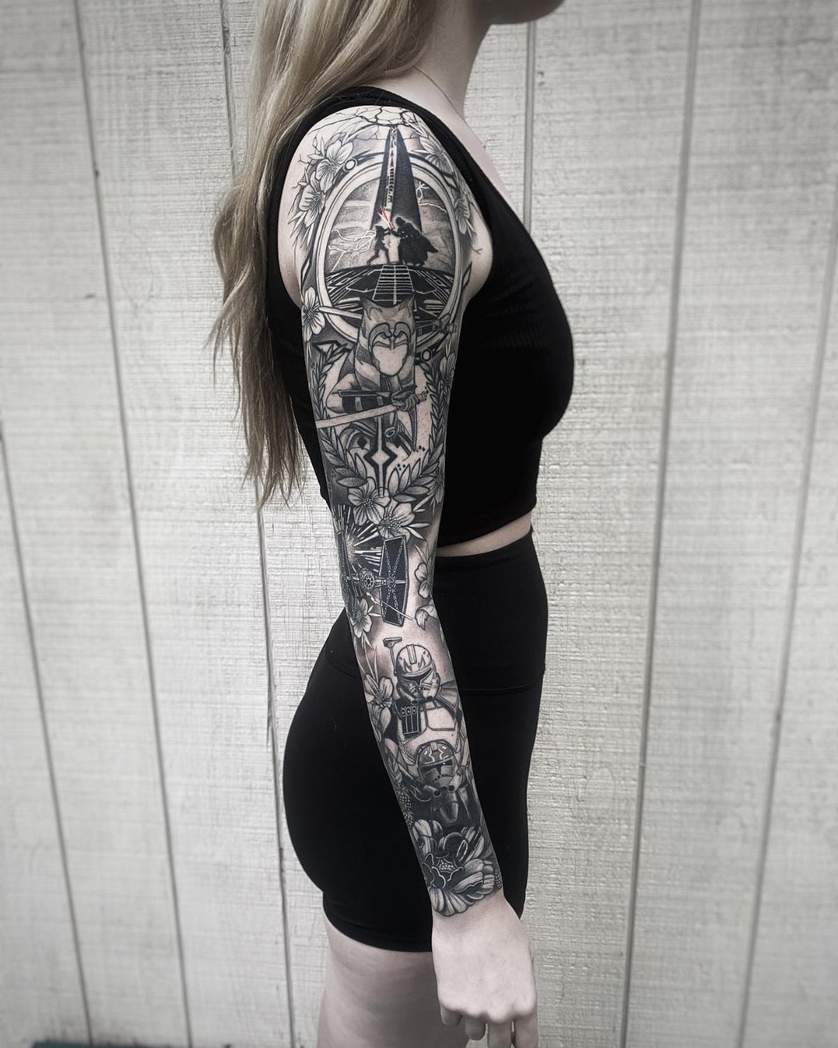Woman's arm with a detailed black and grey Star Wars themed full sleeve tattoo.