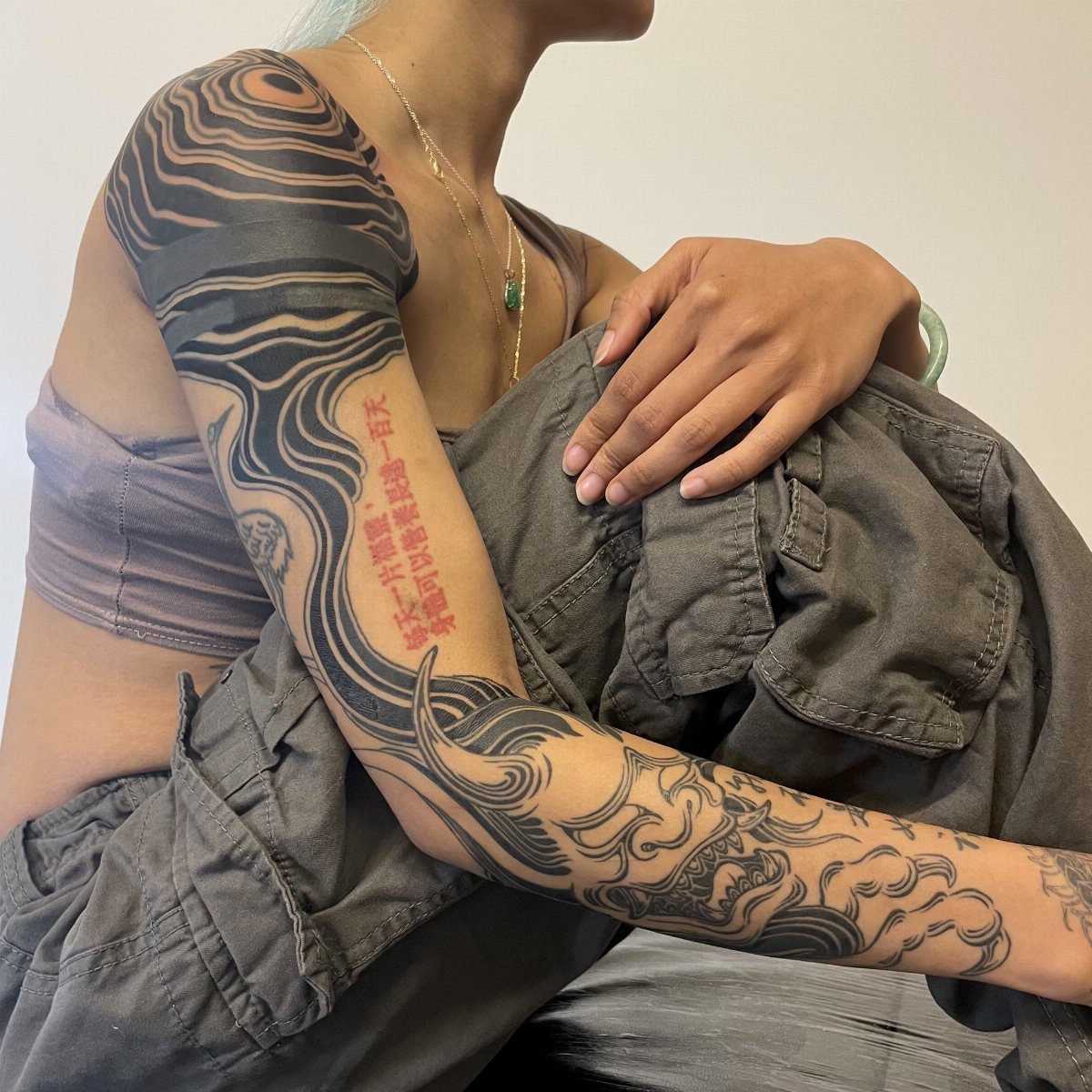 Full sleeve tattoo with swirling black and grey marbling patterns and red Chinese characters.