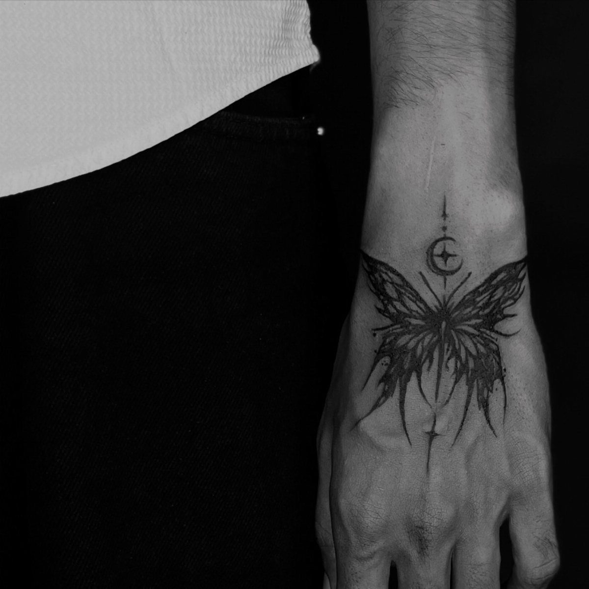 Butterfly tattoo with a crescent moon on a person's wrist and hand.
