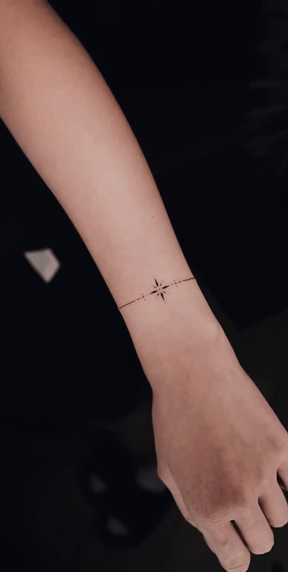 Small star tattoo with a thin line on a person's wrist.