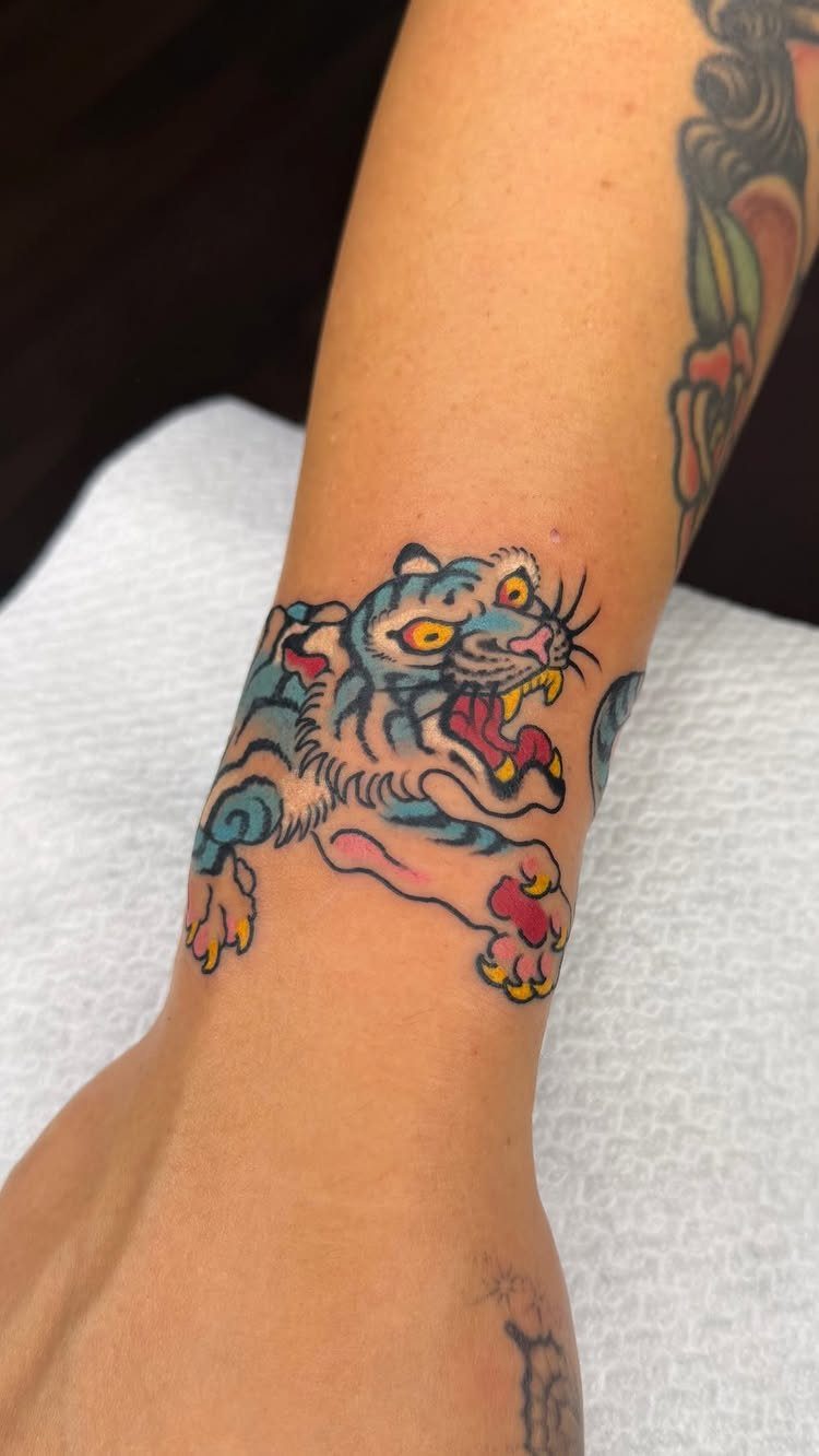 Colorful tiger tattoo on a person's wrist resting on a white towel.