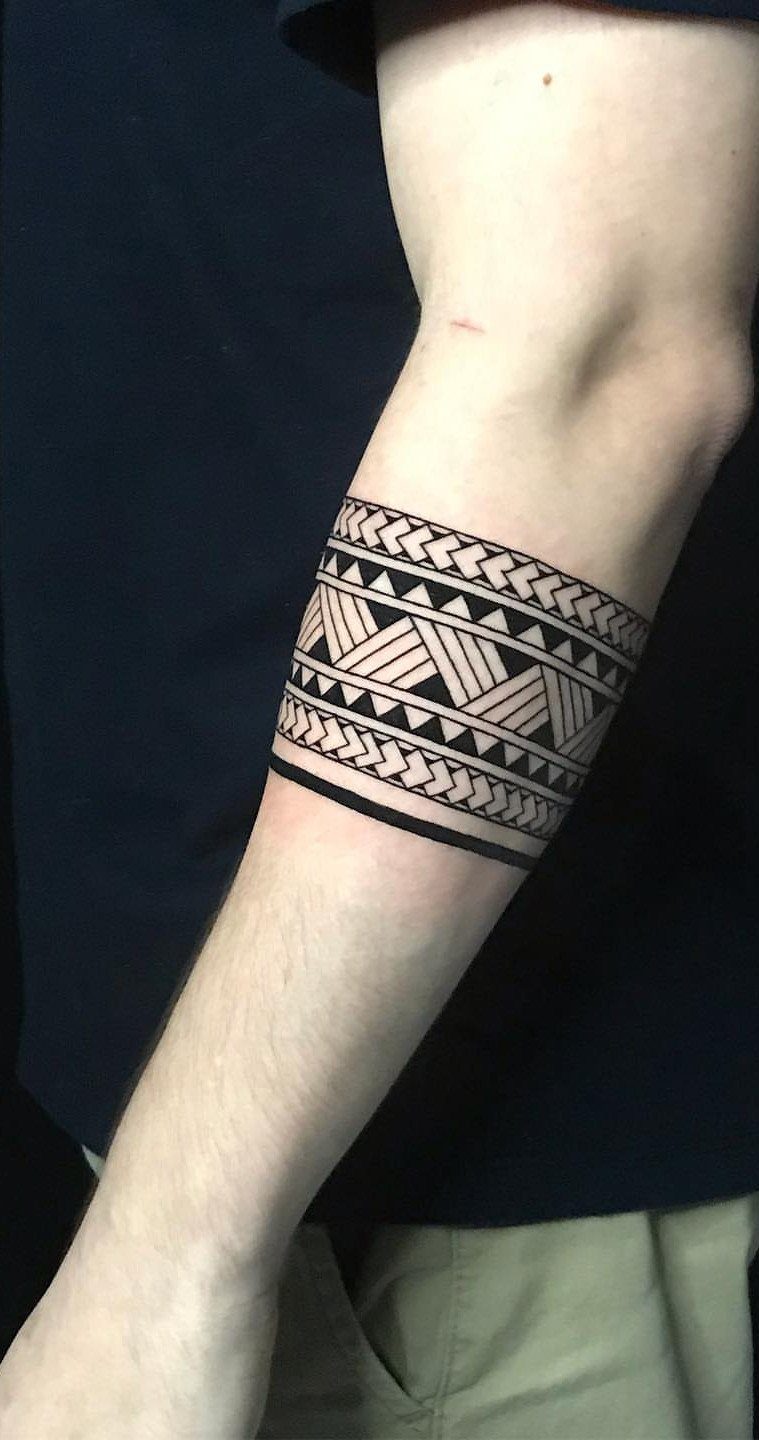 Tribal band tattoo with geometric patterns wrapping around a person's forearm.