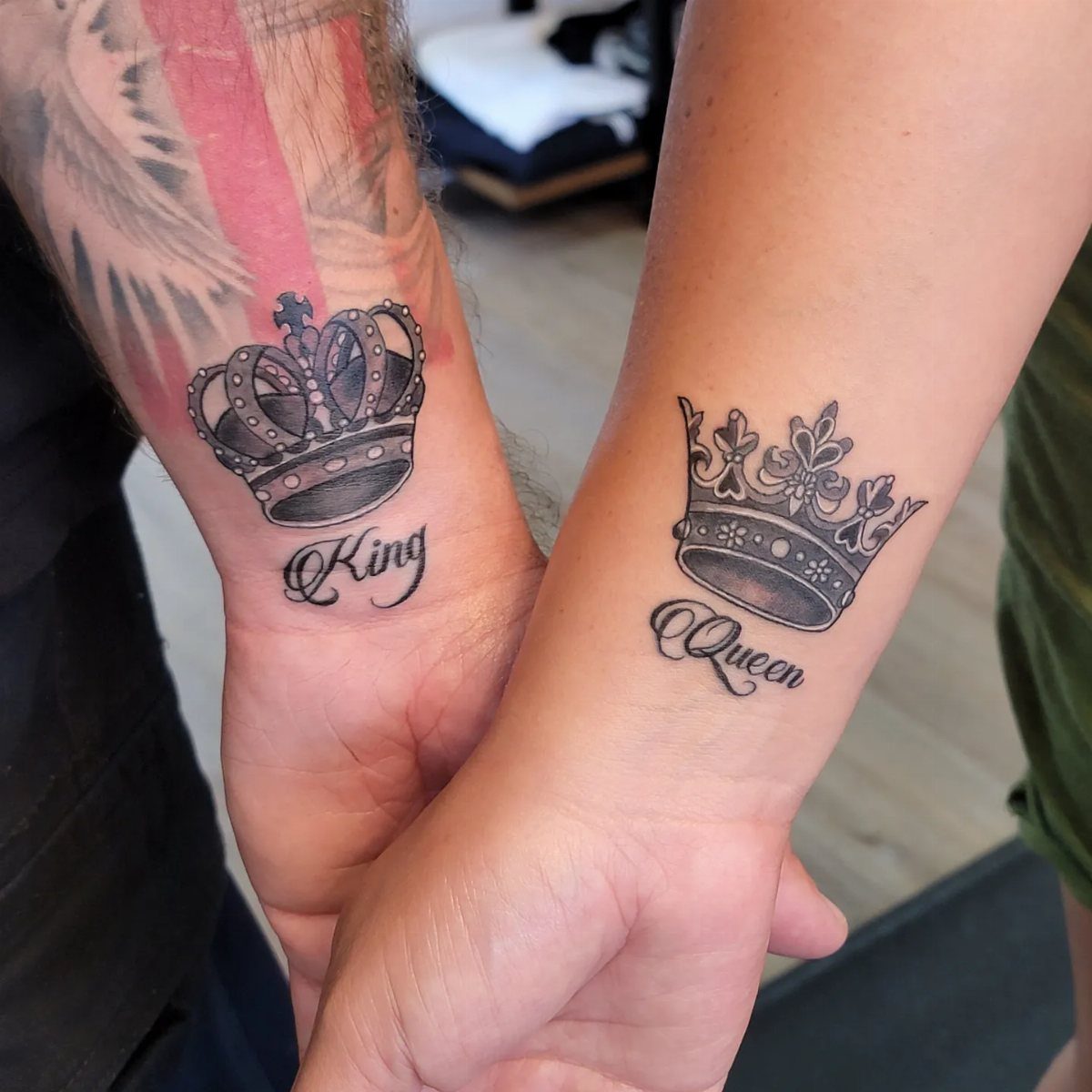 Two wrists with matching crown tattoos labeled King and Queen in black ink.