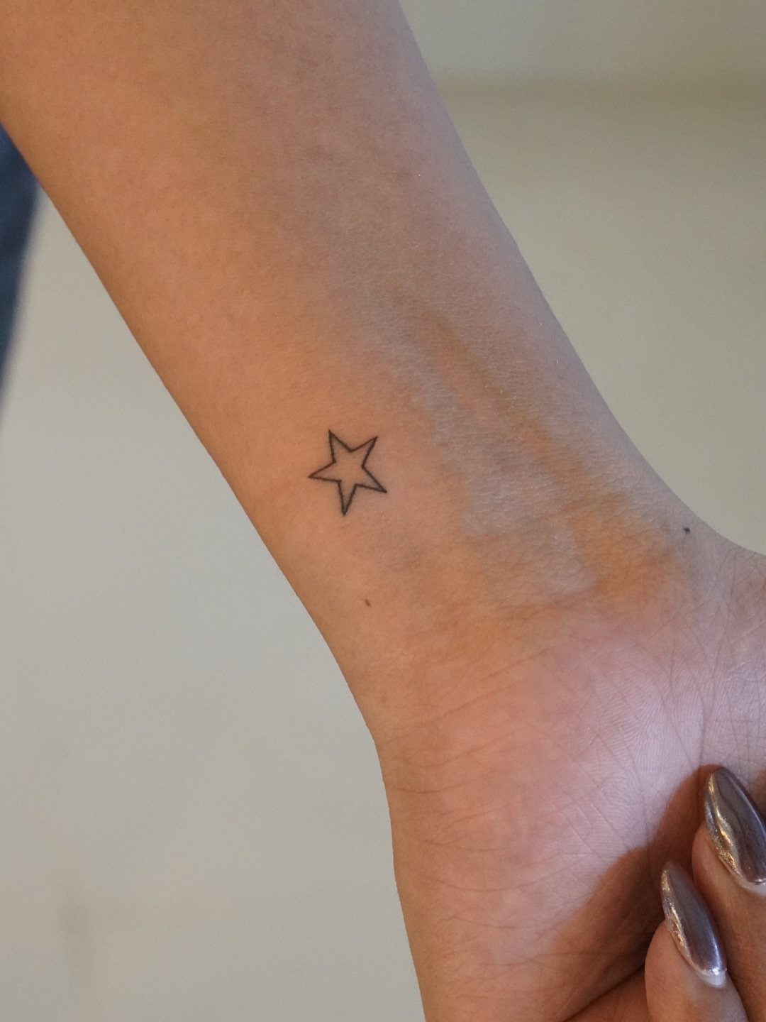 Small black outline star tattoo on a person's inner wrist.